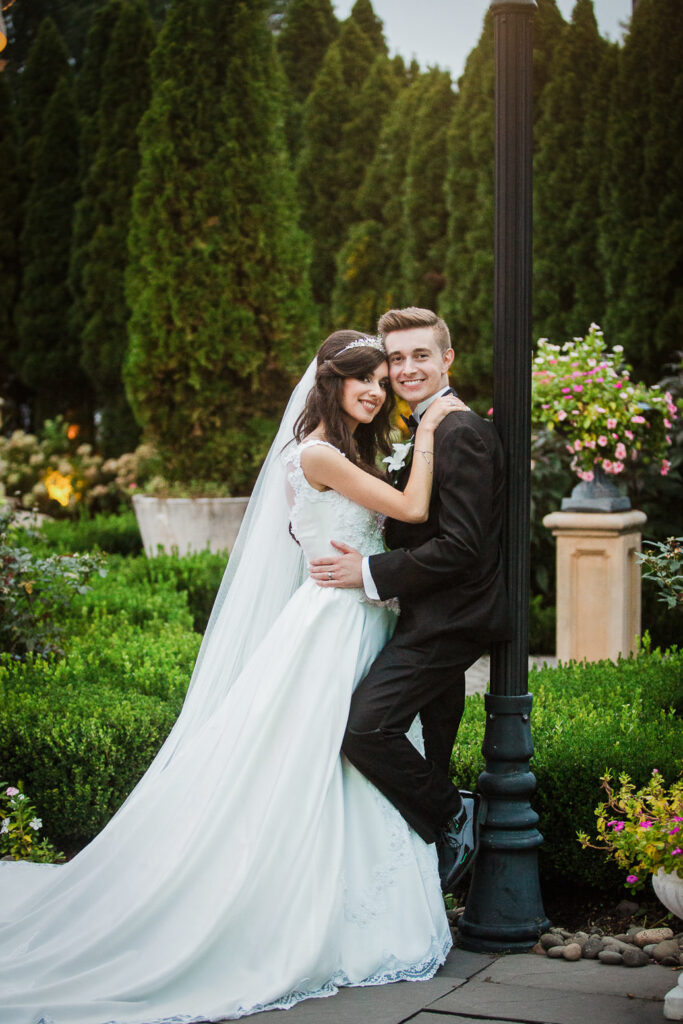 Bride and groom embracing by lamp post at Rockleigh Country Club at sunset
