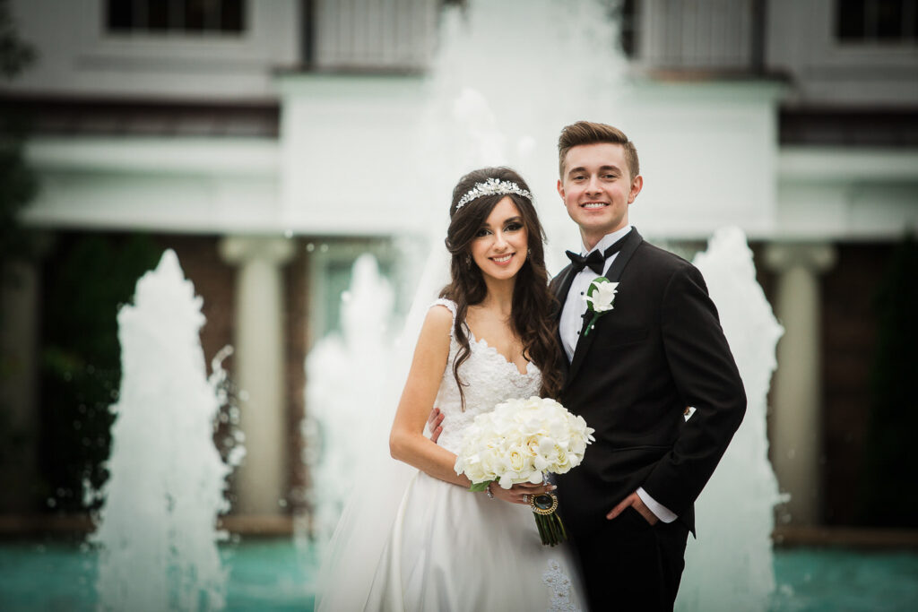 Groom posing with bridesmaids in the gardens at Rockleigh Country Club wedding