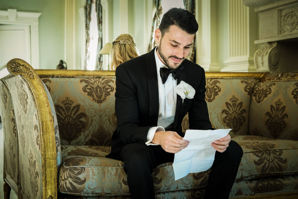 Groom reading vows on couch Rockleigh Country Club