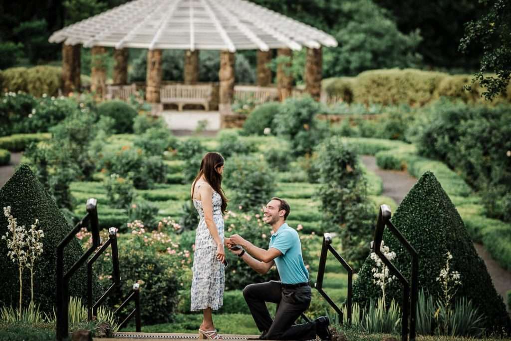 Newly engaged couple embracing immediately after proposal in Northern New Jersey park, captured by proposal photographer Alex Kaplan showing authentic emotional reaction