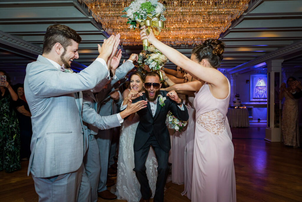 Wedding party creating bouquet tunnel for couple's dramatic entrance into Tides Estate ballroom