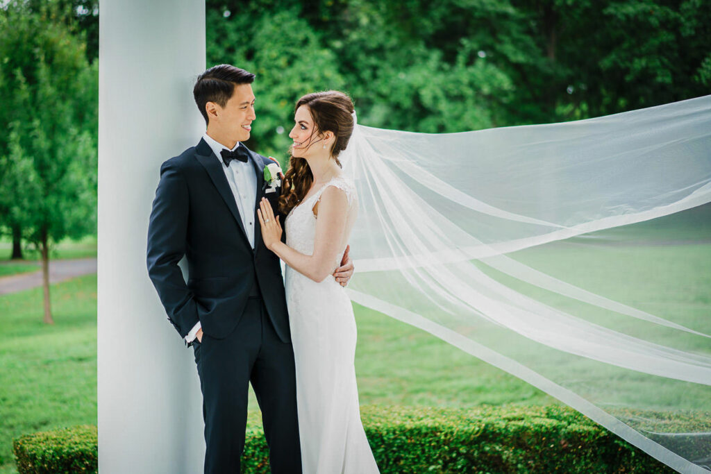 Bride and groom formal portrait with cathedral length veil on rainy wedding day in Glen Cove