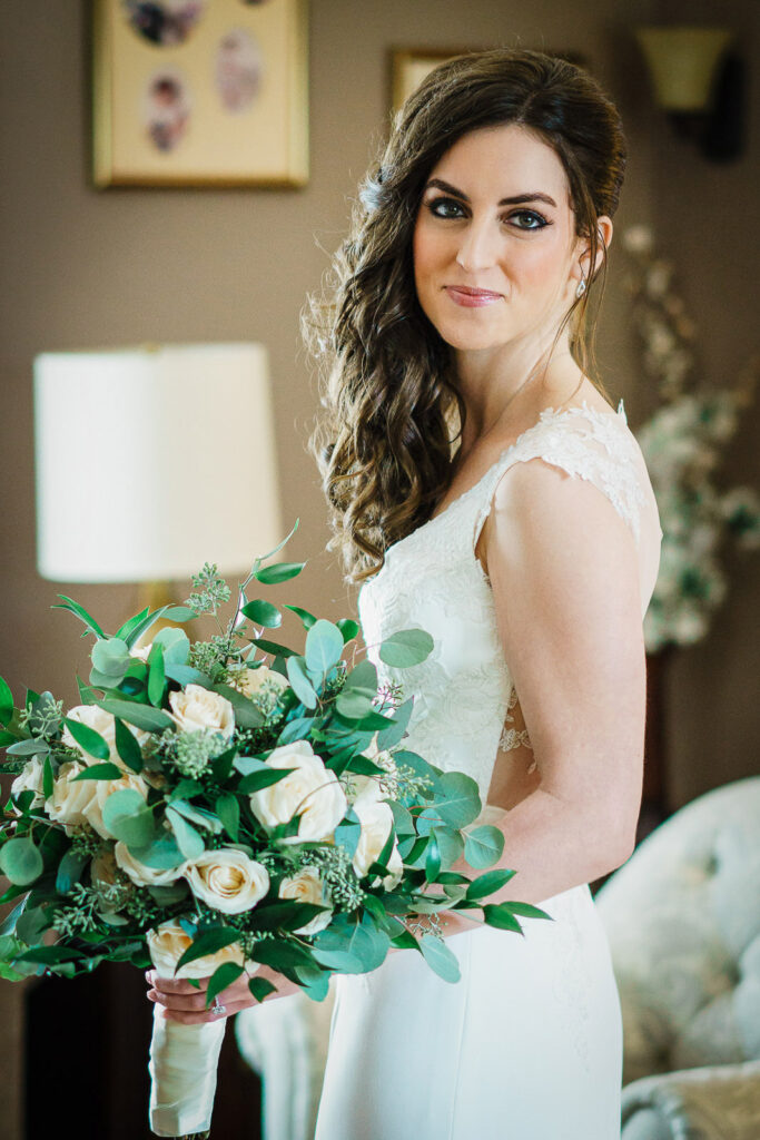 Bride portrait with side-swept curls holding organic eucalyptus and rose bouquet before Metropolitan Caterers wedding