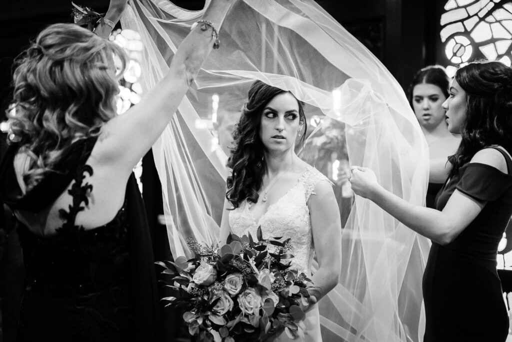 Bride's veil being lifted during reception ceremony moment at Metropolitan Caterers Glen Cove with bridesmaids