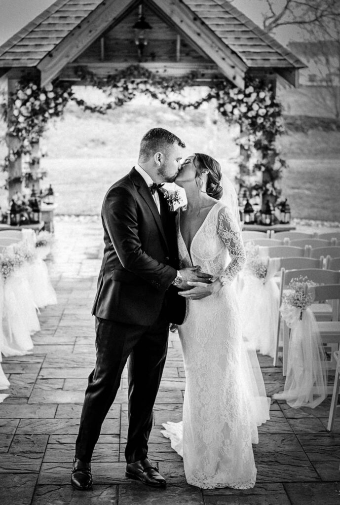 First kiss under floral pavilion at Hamilton Farm Golf Club wedding ceremony