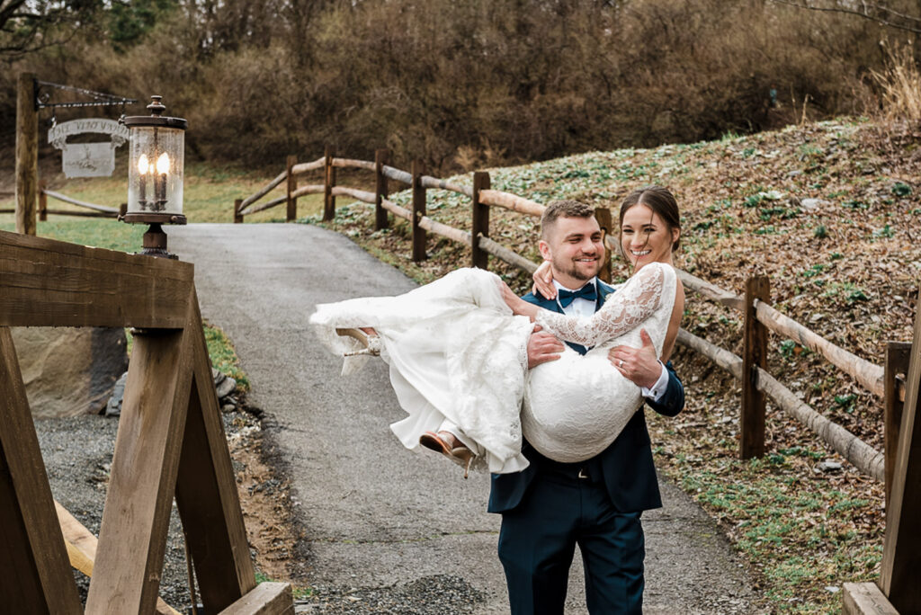 Groom carrying bride on wooden bridge at Hamilton Farm Golf Club