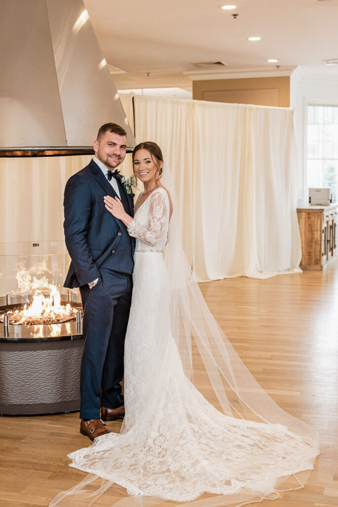 Wedding couple by modern fireplace inside Hamilton Farm Golf Club
