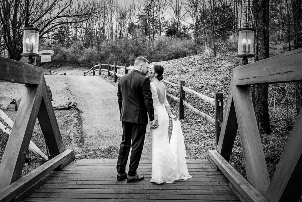 Newlyweds walking and kissing on bridge at Hamilton Farm Golf Club