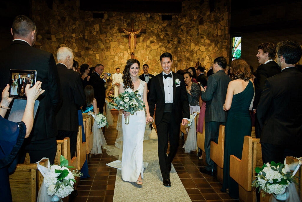 Newly married couple walking down aisle after Catholic church ceremony at Our Lady of Hope Church Glen Cove