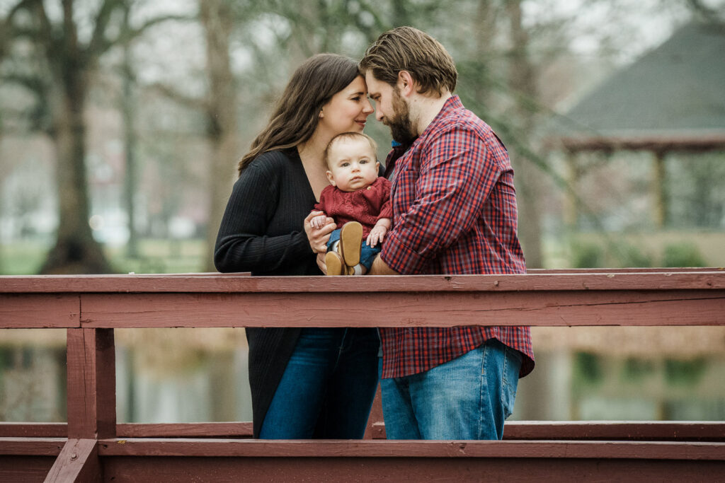 Parents sharing intimate moment with baby on bridge at Knight Park in Collingswood