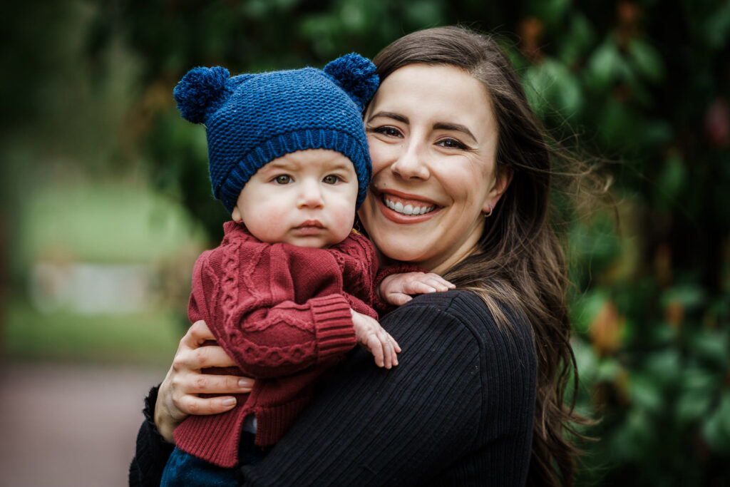 Mother holding baby in blue knit hat at Knight Park in Collingswood NJ