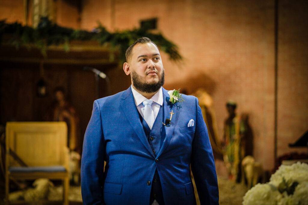 Groom at altar with Christmas poinsettias at St Theresa Church Kenilworth