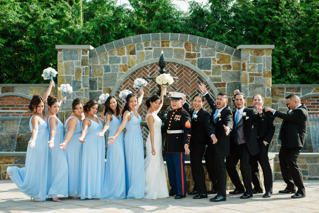 Wedding party celebrating with bouquets raised at Rockleigh Country Club stone fountain