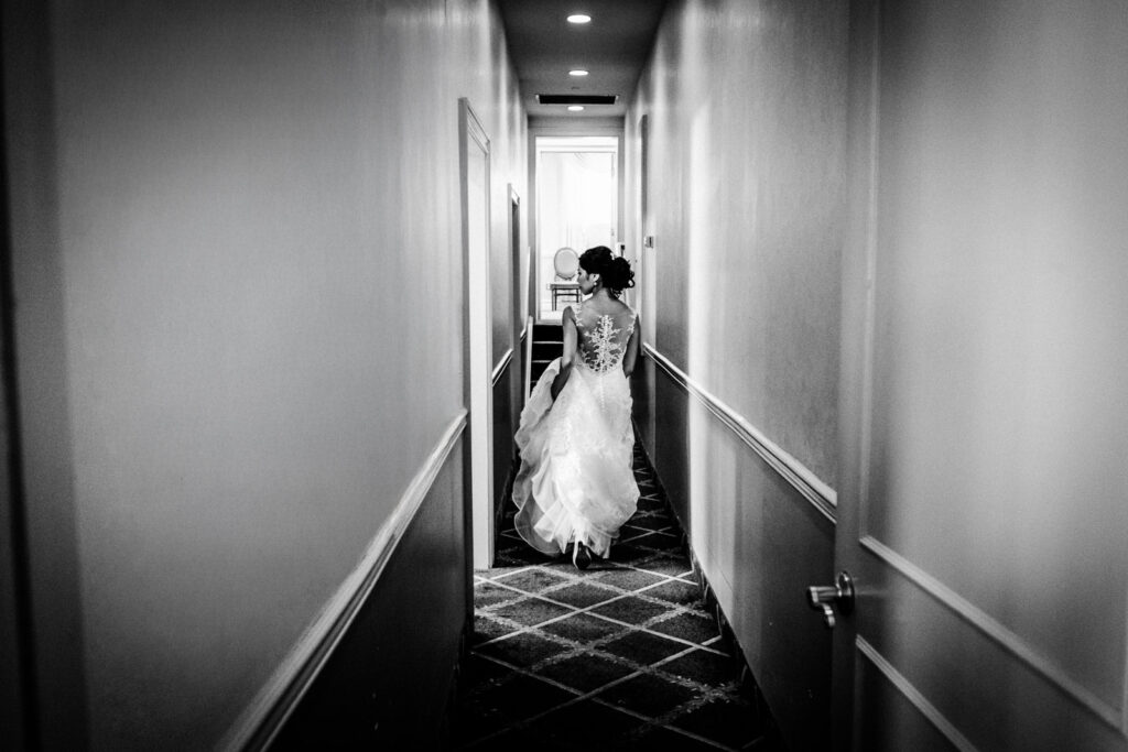 Black and white photo of bride walking down hallway at Rockleigh Country Club