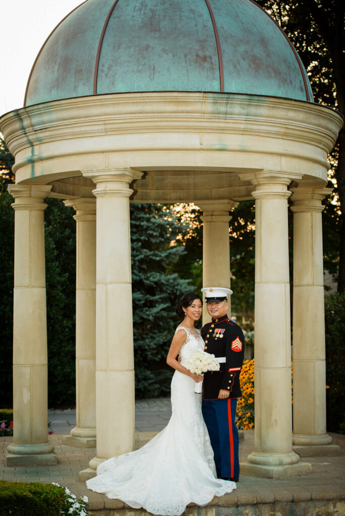 Marine groom kissing bride by fountain at Rockleigh Country Club