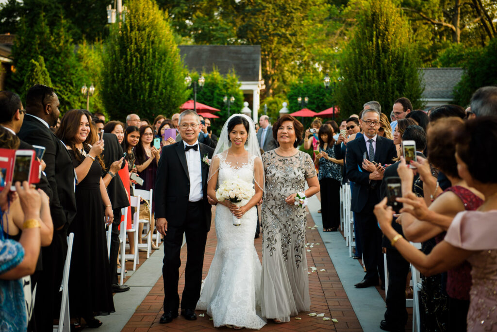Groom walking with parents down aisle at Rockleigh Country Club outdoor ceremony