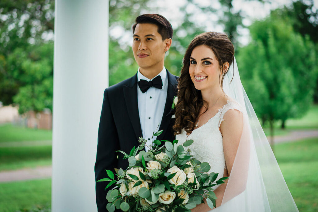 Romantic rainy day wedding portrait with bride's cathedral veil flowing in wind near Our Lady of Hope Church