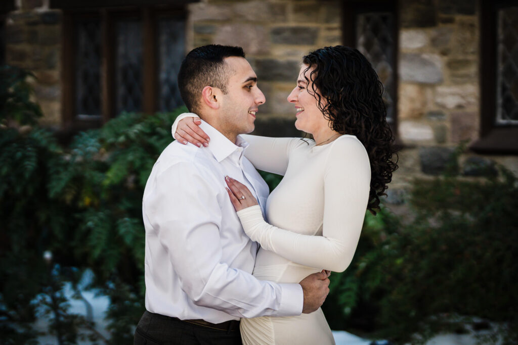 Engaged couple embracing near stone architecture at Skylands in winter, Ringwood NJ
