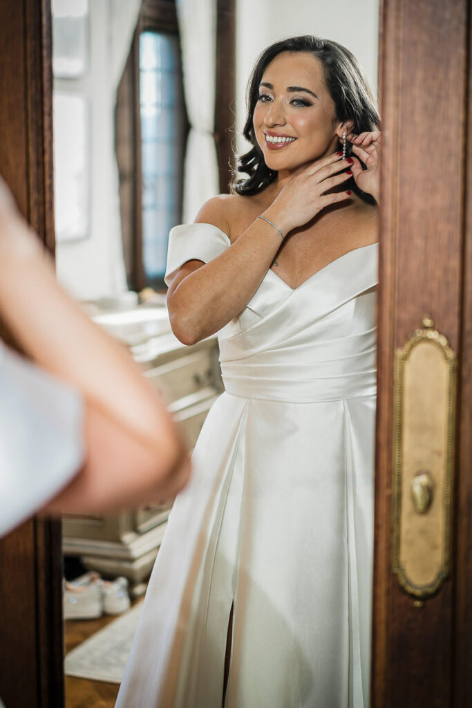 Bride adjusting earring in bridal suite mirror at Skylands Manor