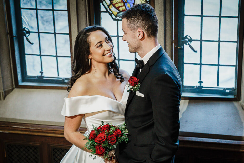 Groom smiling at bride in historic library at Skylands Manor