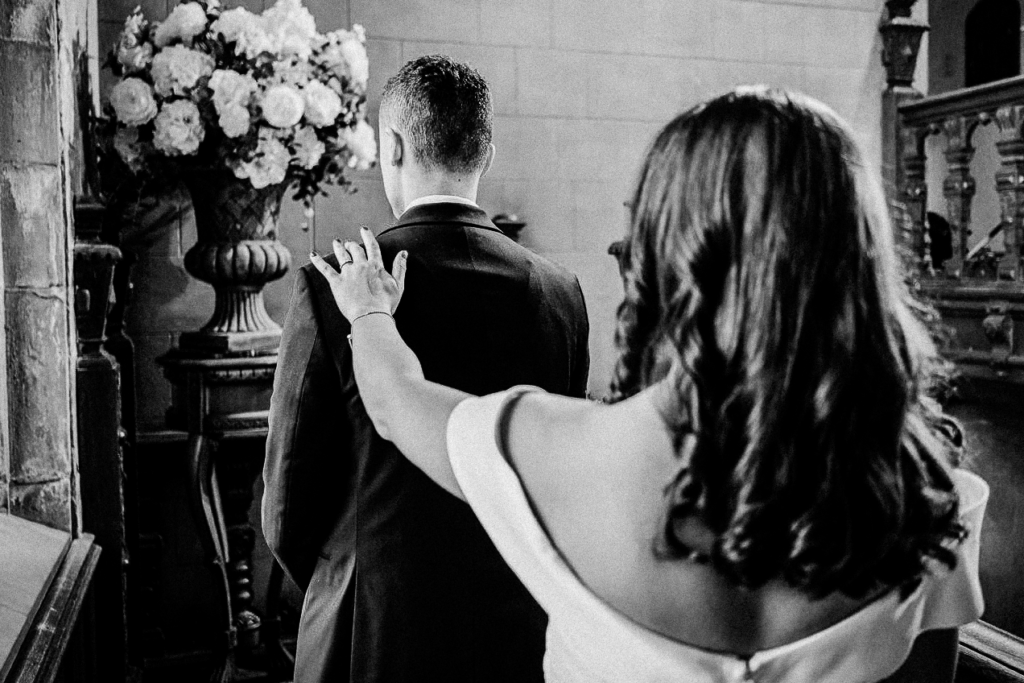 Bride's hand on groom's shoulder during first look at Skylands Manor staircase