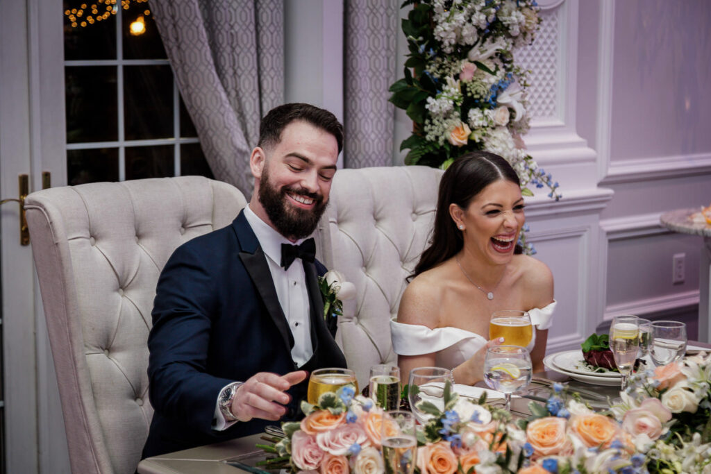 Bride and groom laughing during wedding toasts at reception