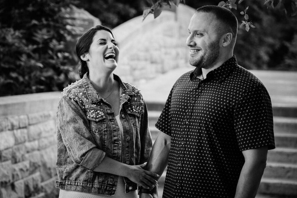 Black and white candid engagement photo at Verona Park in Verona New Jersey showing authentic laughter