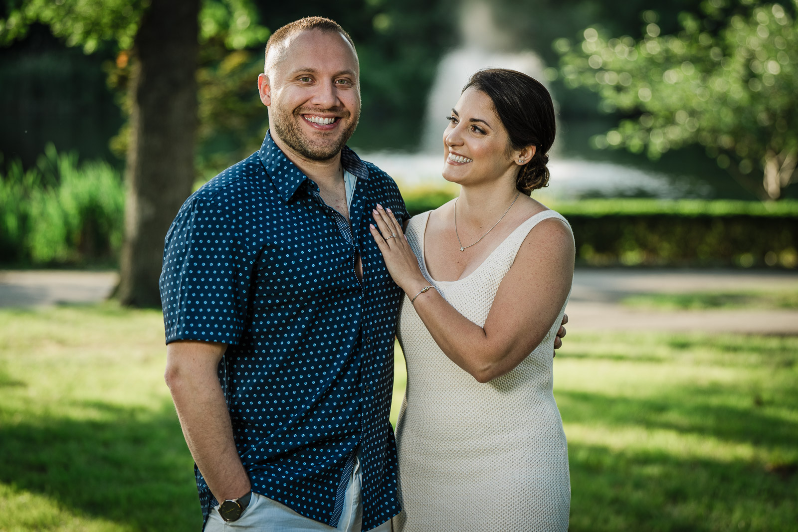 Engaged couple smiling at Verona Park in Essex County New Jersey with lush greenery background