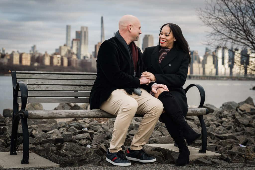 Couple sitting together on waterfront bench at Waterside Restaurant with Manhattan views, North Bergen winter