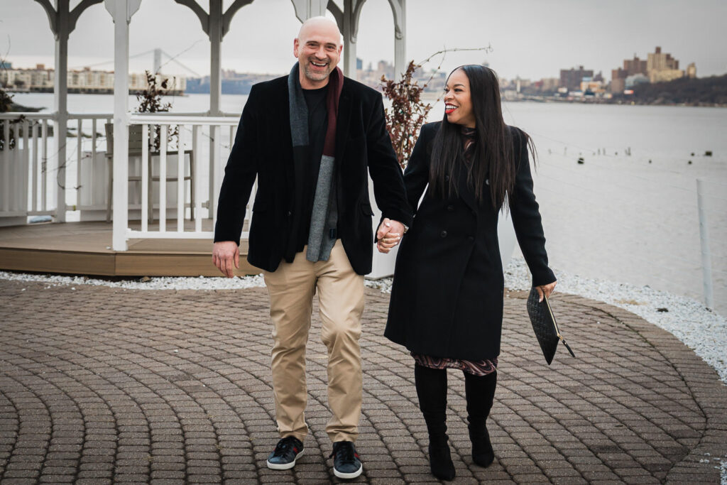 Couple walking hand in hand at Waterside Restaurant North Bergen waterfront after winter proposal