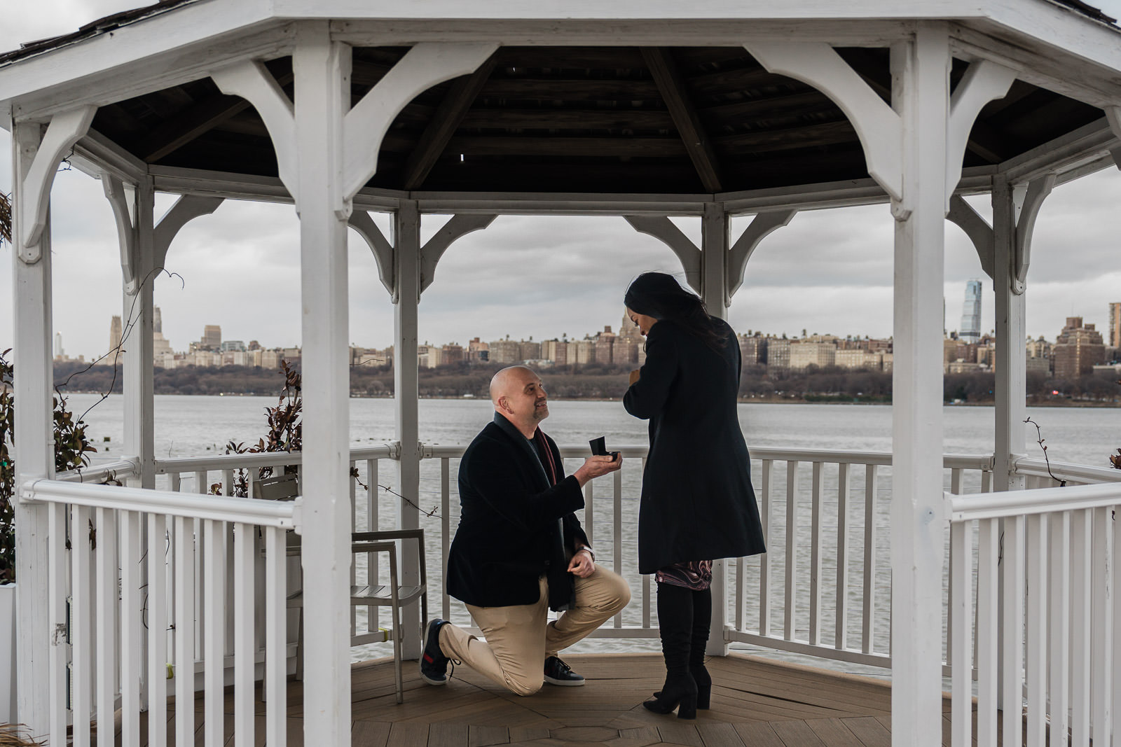 Couple during surprise proposal at Waterside Restaurant gazebo with Manhattan skyline, North Bergen NJ