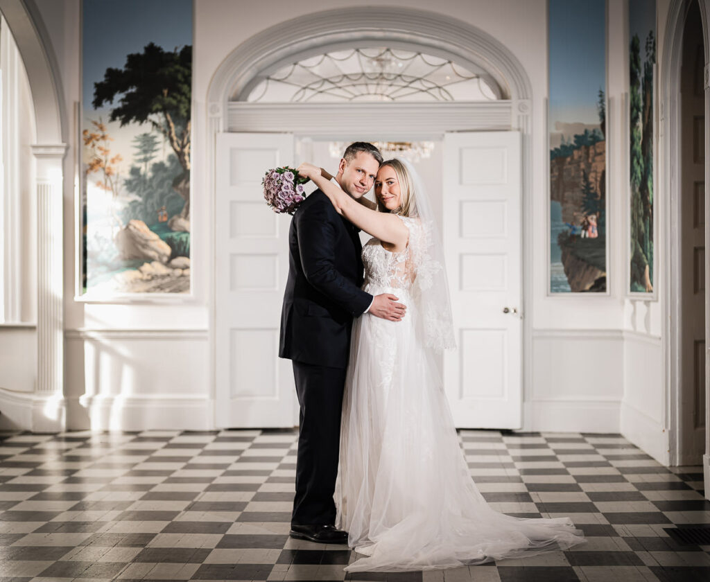 Wedding couple portrait in elegant checkerboard marble foyer with arched doorway and hand-painted scenic murals at Highlands Mansion Fort Washington
