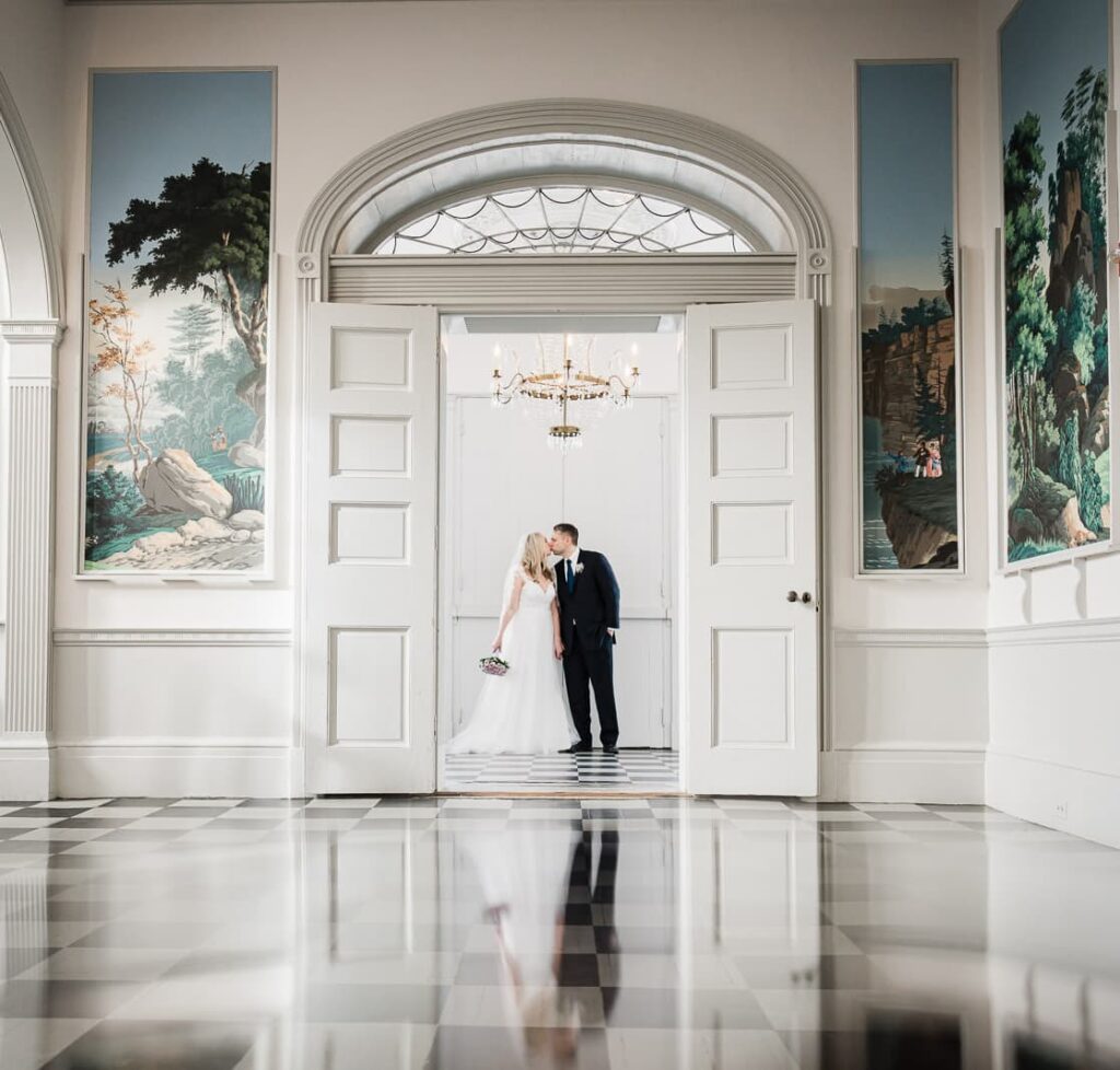 Wide angle wedding portrait in grand foyer with crystal chandelier and scenic wall murals at Highlands Mansion Gardens Pennsylvania