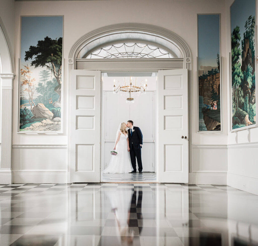 Wide angle wedding portrait in grand foyer with crystal chandelier and scenic wall murals at Highlands Mansion Gardens Pennsylvania