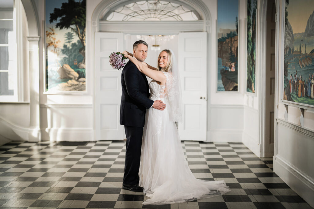 Newlyweds embracing in natural window light at The Highlands Mansion and Gardens Fort Washington PA