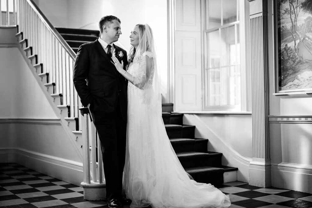 Black and white wedding portrait of newlyweds on elegant historic staircase at Highlands Mansion Fort Washington Pennsylvania
