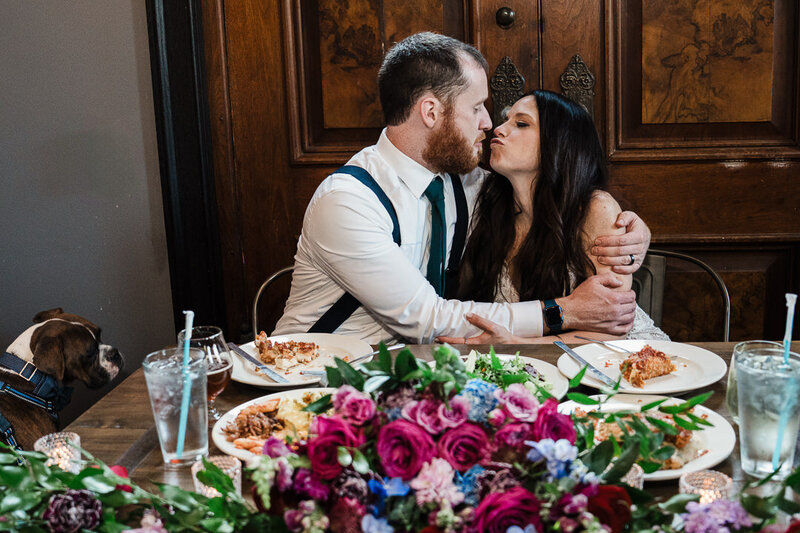 Bride and groom sharing a kiss at the sweetheart table with an elegant floral centerpiece at a New Jersey wedding receptio