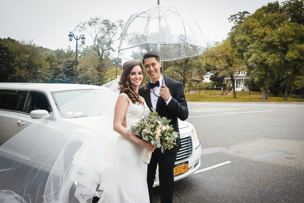 ride and groom posing under a clear umbrella on a rainy wedding day