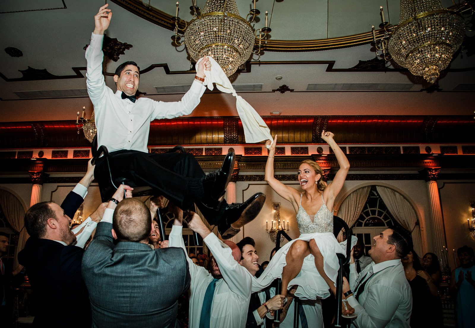 Bride and groom lifted in chairs during the hora at Crystal Plaza wedding reception in Livingston NJ