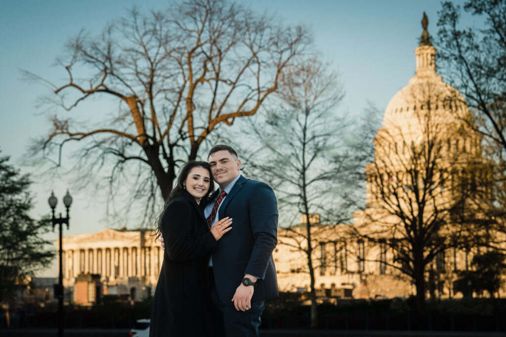 Woman leaning her head on her partner's shoulder near the Capitol dome in golden winter light Washington DC