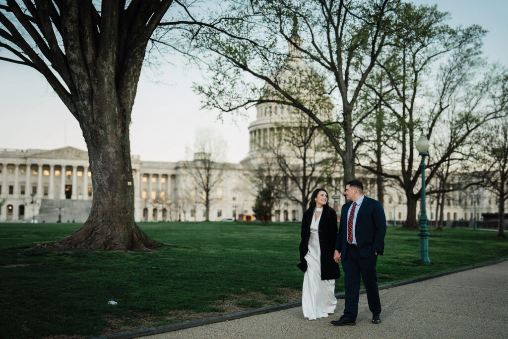 Couple walking hand in hand on a tree-lined path near the US Capitol in spring Washington DC