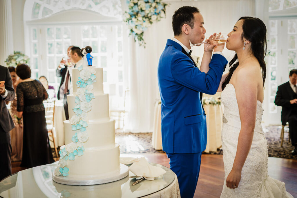 Bride and groom toasting with champagne beside their wedding cake at Crystal Plaza in Livingston NJ