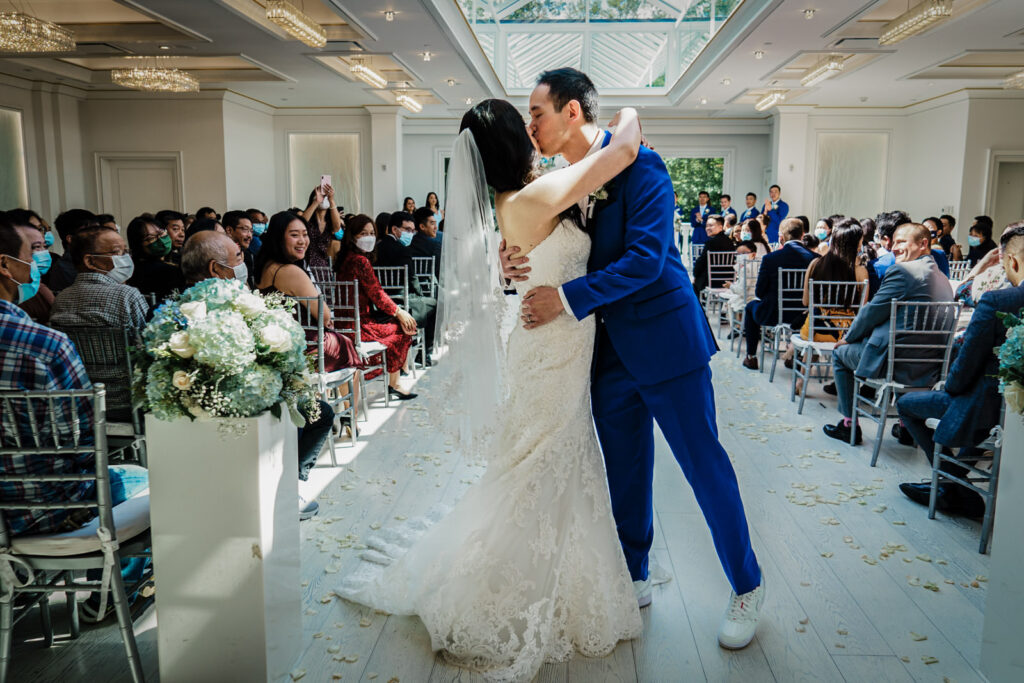 Bride and groom sharing their first kiss under the Crystal Plaza ceremony room skylight in Livingston NJ