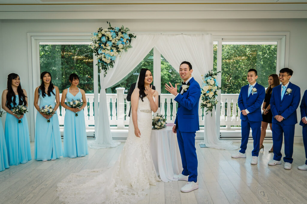 Bride and groom smiling and showing their wedding rings to guests during their Crystal Plaza ceremony in Livingston NJ