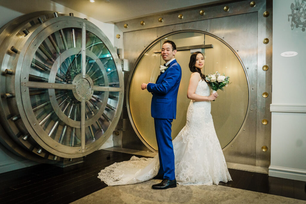 Bride and groom posing in front of the Crystal Plaza vault room door during their wedding portrait session in Livingston NJ