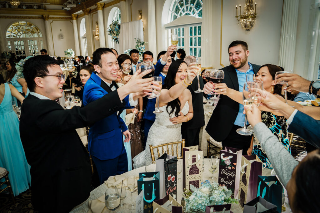 Bride and groom raising glasses with family and guests during a wedding toast in the Crystal Plaza ballroom in Livingston NJ