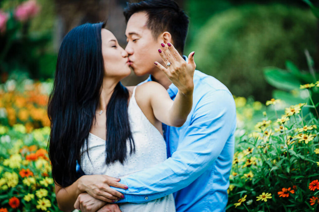 Newly engaged couple kissing and showing engagement ring at Deep Cut Gardens NJ