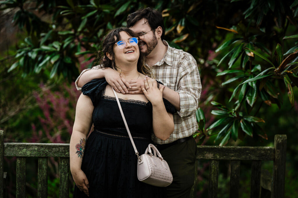 Man embracing partner from behind as she laughs in lush garden at Reeves-Reed Arboretum Summit NJ