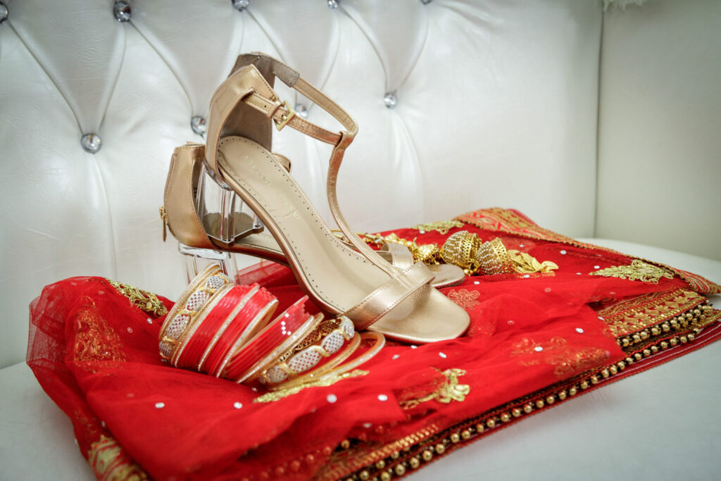  Indian bridal details including gold heels red bangles and embroidered dupatta before multicultural wedding ceremony