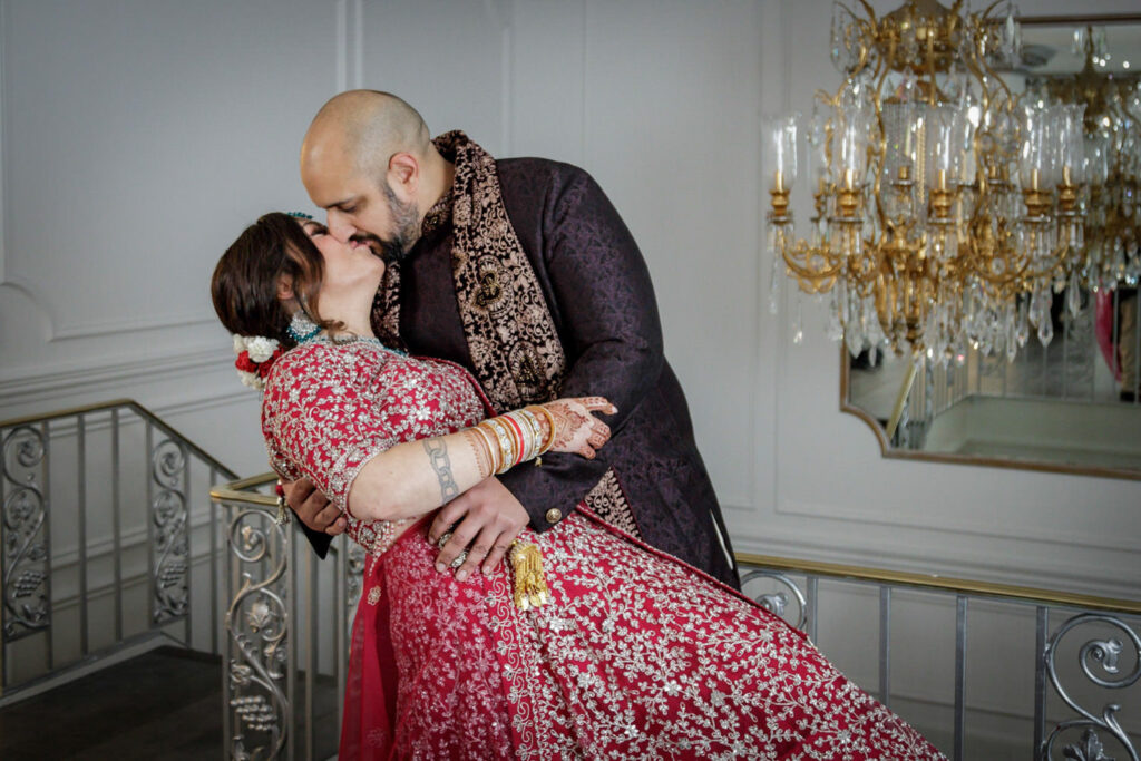 Wedding couple sharing a dip kiss beside ornate gold chandelier at Crystal Plaza NJ